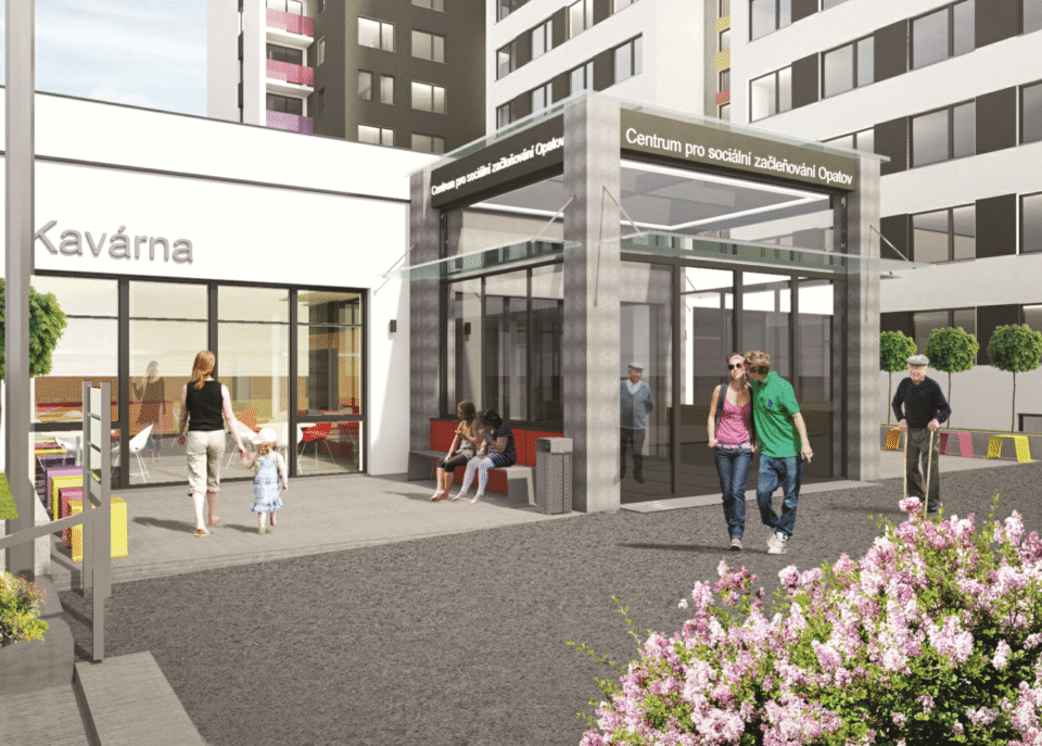 Venkovní pohled na centrum pro sociálně zdravotní služby s kavárnou lidé procházejí kolem květin a moderní budovy což vytváří přívětivé prostředí pro návštěvníky